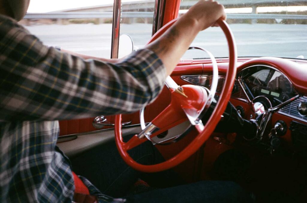A man driving a classic car with red interiors