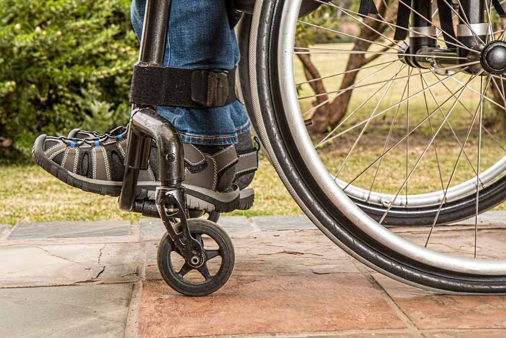 A disabled individual sitting in a wheelchair in an outdoors environment