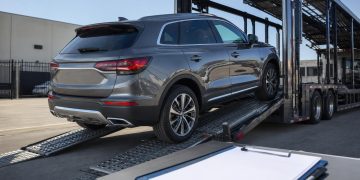 Online vehicle purchase being loaded onto an open auto transport carrier
